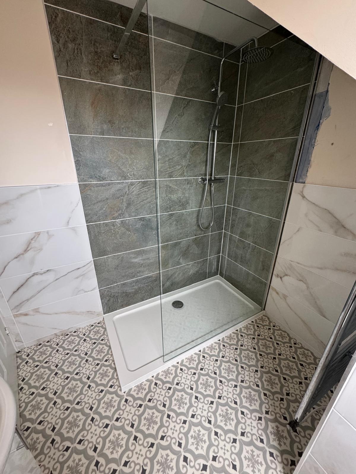 Slate-effect shower wall tiling and patterned floor tiles laid during a bathroom refit